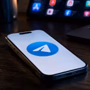 Телефон iPhone с логотипом Telegram на экране