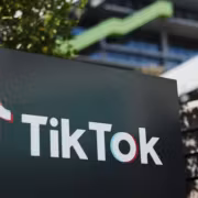 Стенд с логотипом TikTok рядом с деревьями и зданием