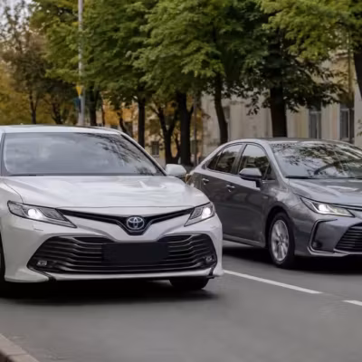 Два автомобиля Toyota Corolla в серых и белых цветах на городской дороге