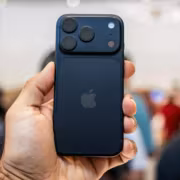 Apple и конкуренты подняли цены на смартфоны на $100 3 Человек держит синий iPhone на мероприятии