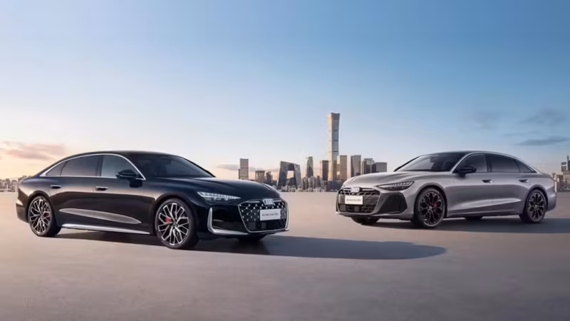 Два автомобиля Audi A6 L на фоне города в небе