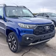 Нива Тревел 2029 года на парковке рядом с серым авто