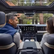 Внутри электромобиля GM Chevrolet Silverado и GMC Sierra 2027 автомобиля показывают сенсорный экран и два человека разговаривают