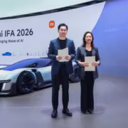 Двух человек на сцене у зеленого автомобиля на выставке Xiaomi IFA 2026