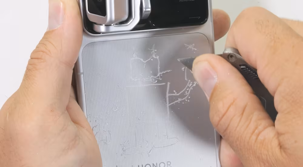 JerryRigEverything испытал смартфон Honor Robot Phone с помощью песка и разобрал его 16 Человек царапает экран Honor Robot Phone ножом