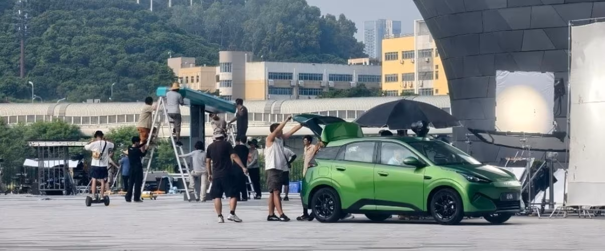 группаPeople монтажники рабочие рядом с зеленая BYD Seagull на площадке