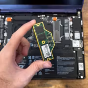 человек держит SSD диск для ноутбука на деревянном столе