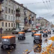 Роботы-доставщики на улице с осенними листьями и пешеходами
