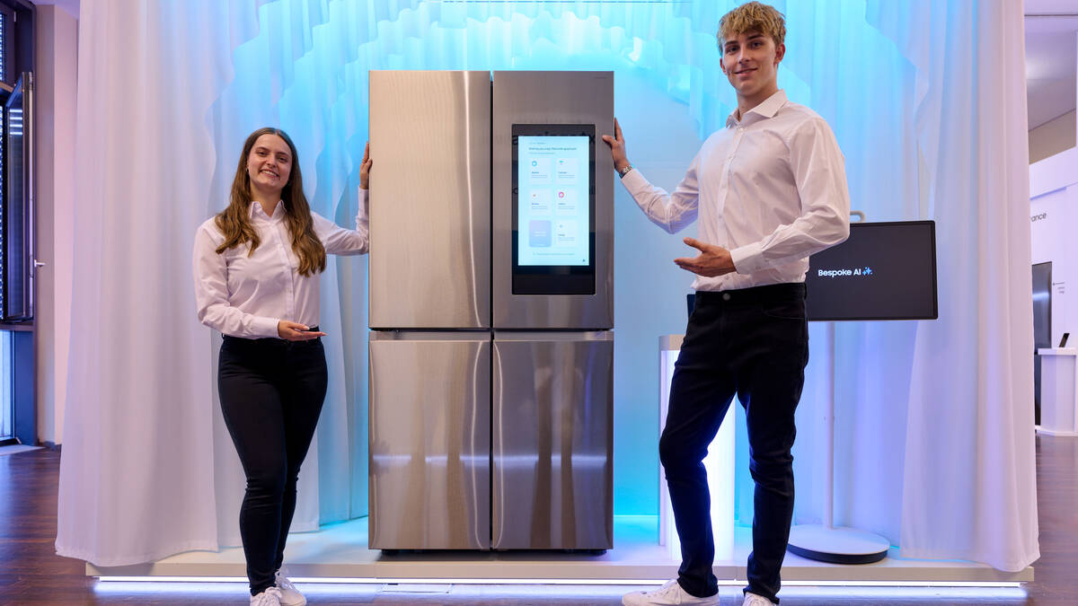 Два человека демонстрируют холодильник Samsung с сенсорным экраном Samsung AI Living