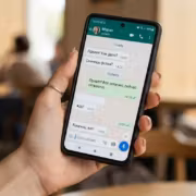 Человек держит смартфон с открытым WhatsApp на экране