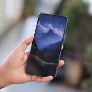 Galaxy A57 начала получать One UI 9 на Android 17 в Европе 3 Человек держит смартфон Samsung Galaxy A57 с горным пейзажем на экране