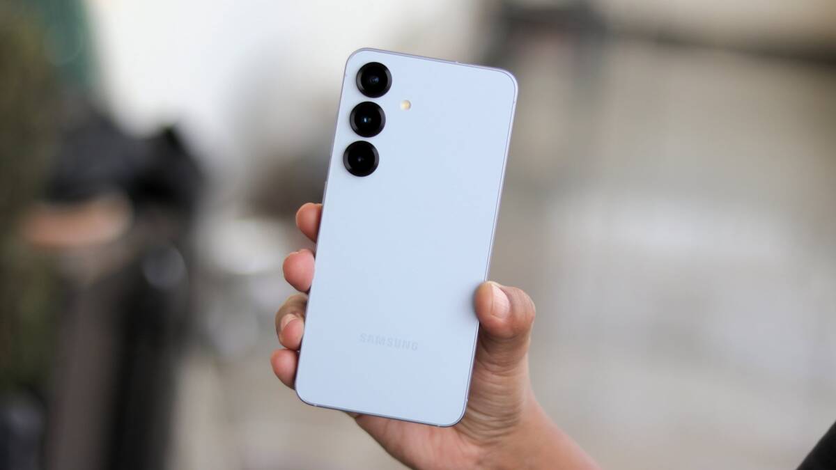 Человек держит белый Samsung Galaxy S25 с тремя камерами