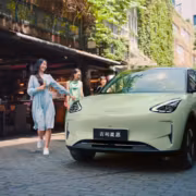 Девушка с мороженым возле зелёного автомобиля Geely EX2