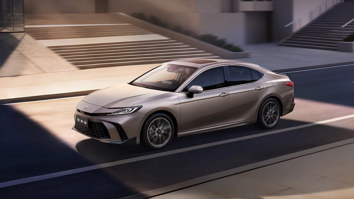 Гибридная Toyota Camry серебристого цвета на дороге
