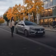 Lada Vesta сертифицировали с моторами «Евро-6» мощностью до 132 л. с. 5 Женщина идет по тротуару возле автомобиля Лада Веста в центре города осень
