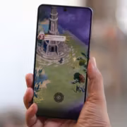 Смартфон с экраном, отображающая игровой интерфейс, рука держит устройство