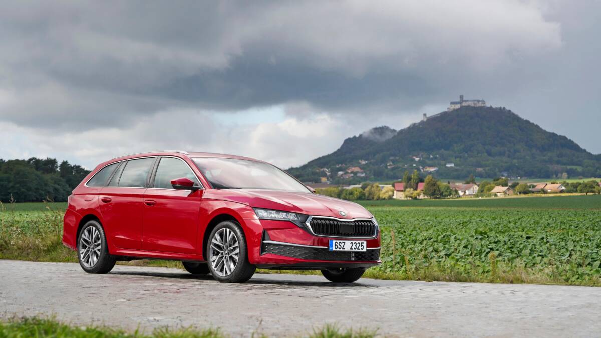 Skoda Octavia впервые получила полный гибрид с запасом хода до 2 км на электричестве 3 Красный Škoda Octavia на серой дороге на фоне холмов и облачного неба