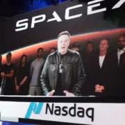 Экран с логотипом Nasdaq и людьми на конференции SpaceX