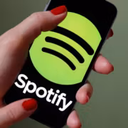 Человек держит смартфон с логотипом Spotify и QR-кодом