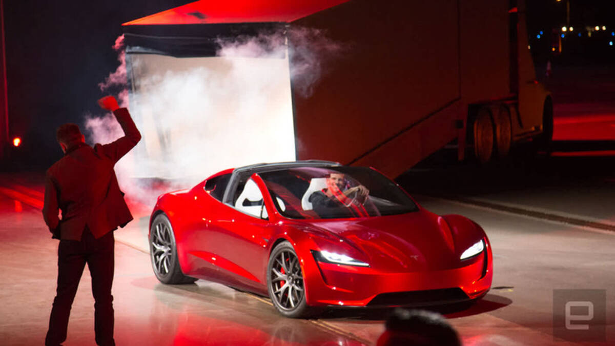 Красная Tesla Roadster на сцене со сцеплением и человеком в кэжуале