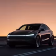 Черный электромобиль Tesla на дороге у гор при закате