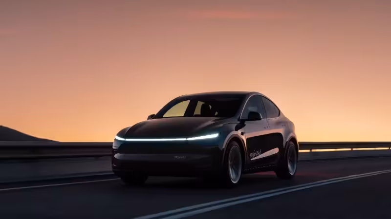 Черный электромобиль Tesla на дороге у гор при закате