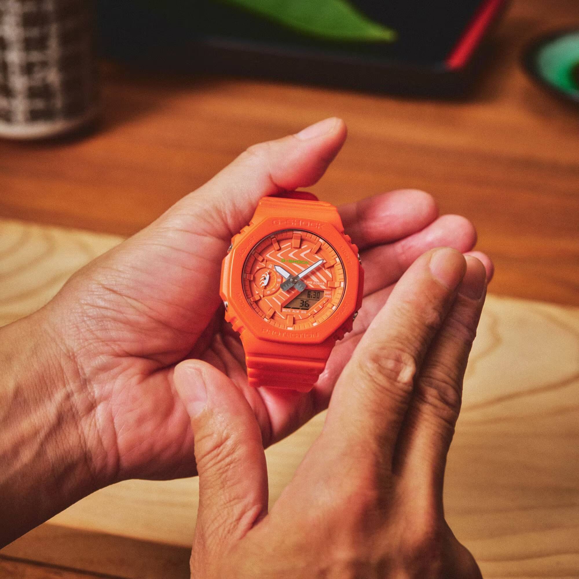 Мужчина показывает часы G-Shock в руке оранжевые