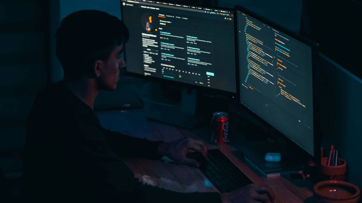 Человек работает за двумя мониторами с кодом eMudhra